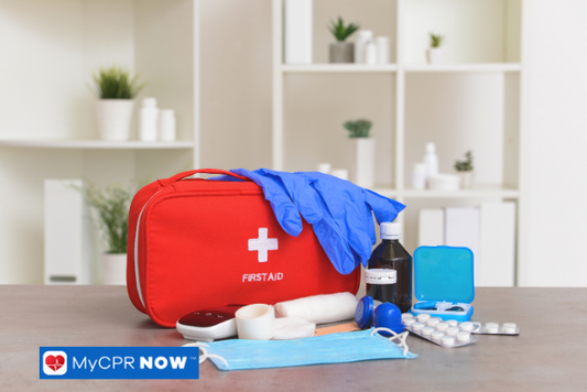 A red first aid kit with gloves, bandages, and other medical items on a table.