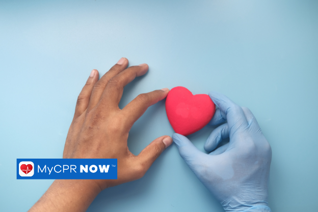Gloved hand holding a red heart on a blue background.