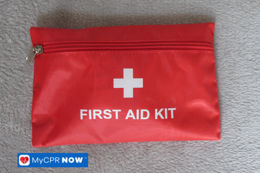Red zippered first aid kit on a soft gray surface.