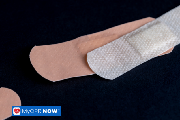 Close-up of adhesive bandages, one partially peeled, against a dark background.