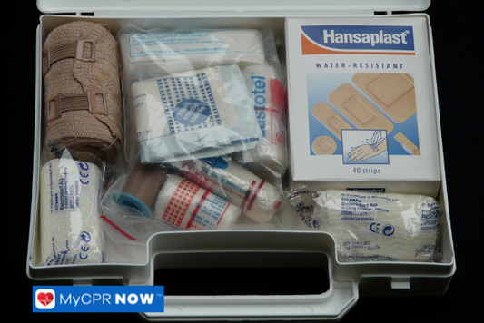 An open white first aid box containing medical supplies, including bandages and antiseptic wipes.