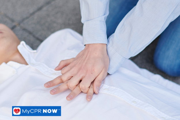 Hands performing CPR on person in white shirt.