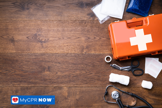An orange first aid kit with medical supplies on a wooden surface.