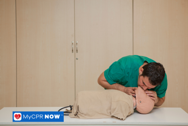 CPR training with a rescuer holding the mannequin's head for airway support.