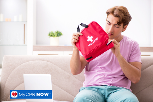 A man sitting on a couch examining a red first aid kit.