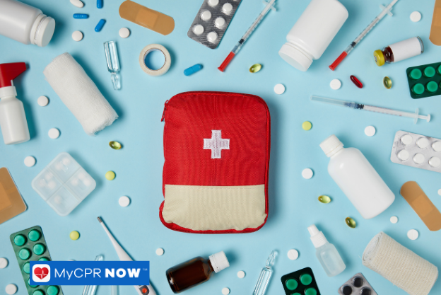 A red first aid kit surrounded by scattered medical supplies on a blue background.