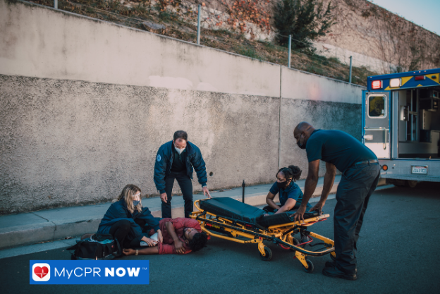 Paramedics assisting injured person on roadside near stretcher.