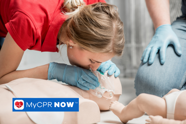 A woman demonstrating CPR techniques in a class on a dummy