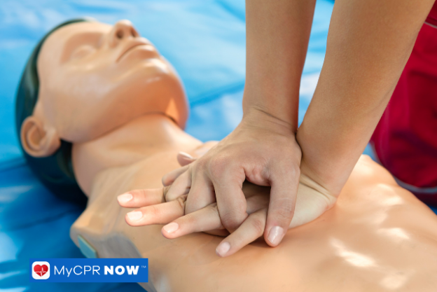 Hands pressing on the chest of a CPR training manikin.