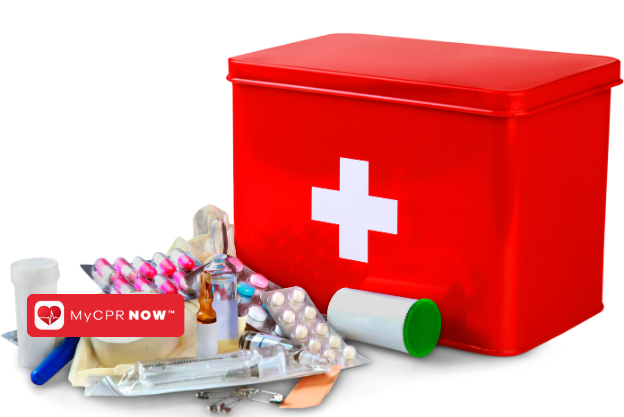 A red first aid kit with supplies in front of it like pills, a syringe, bottles, adhesive bandage, and medical tape. 