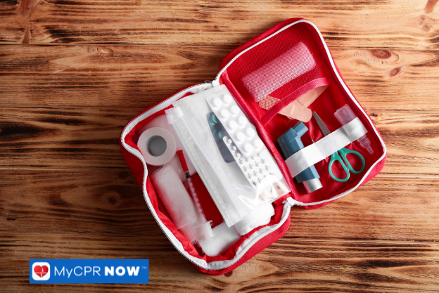 Open first aid kit on a wooden surface containing medical essentials.