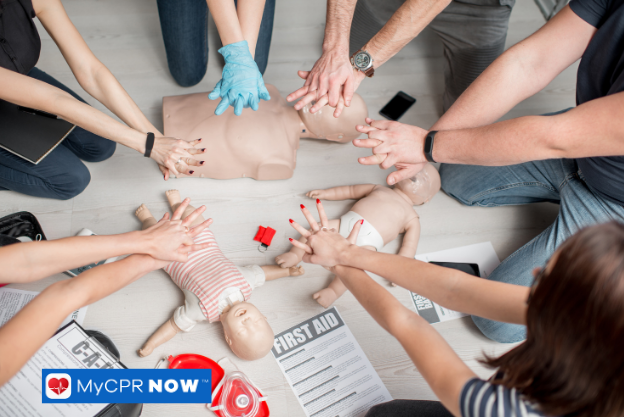 People practicing chest compressions on adult and infant CPR manikins placed on the floor.
