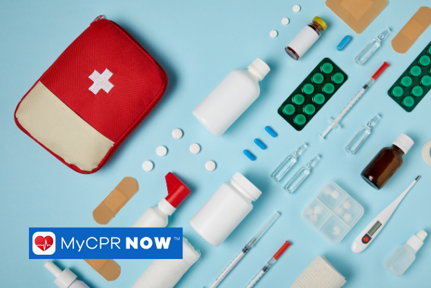 A red first aid kit with first aid supplies lined up next to it on a light blue background. 