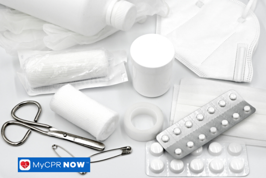Medical supplies including gauze, tape, scissors, and tablets on a white surface.