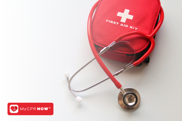 A red stethescope around a red first aid kit. 