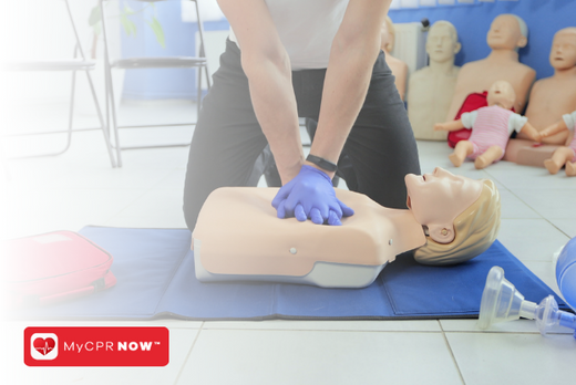 A person in a CPR class with CRP mannequins practicing chest compressions on a mannequin.   