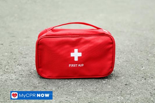 A closed red first aid bag on an outdoor surface.