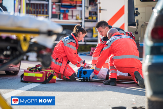 Paramedics attending to a patient on the street.