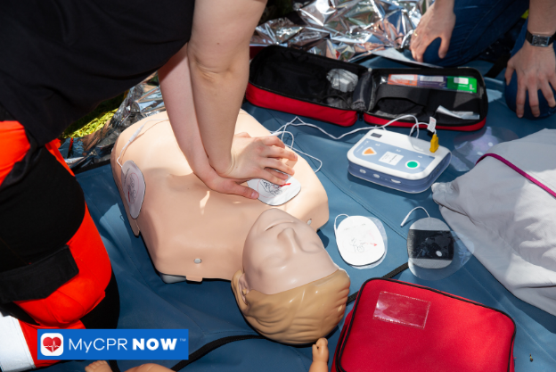 CPR training with a manikin and AED equipment outdoors.