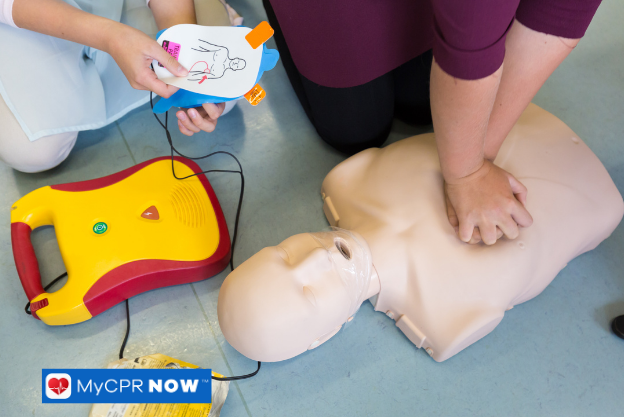 CPR training with AED demonstration on a manikin.