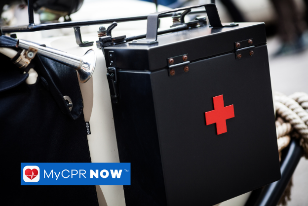 A black first aid kit with a red cross on the front hanging on the side of something. 