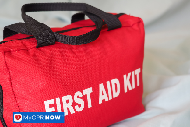 Red fabric first aid kit with black handles placed on a soft surface
