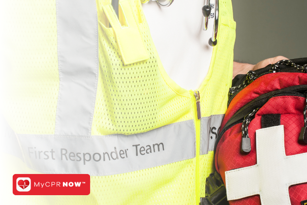 Someone wearing a reflective vest holding a red first aid kit.