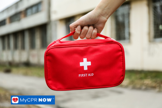 Red first aid kit being held outdoors.
