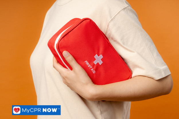 Person holding a red first aid kit against an orange background