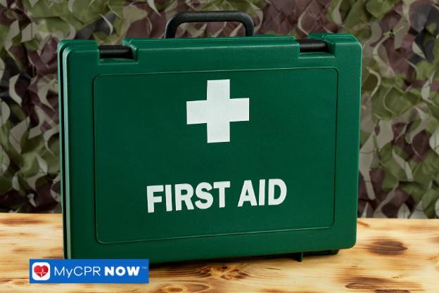 Green first aid kit on a wooden surface with camouflage background.