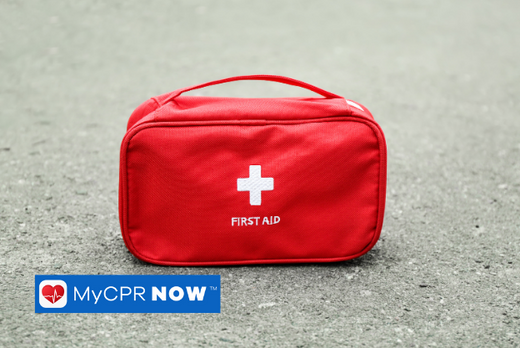 A red first aid kit on the concrete ground. 