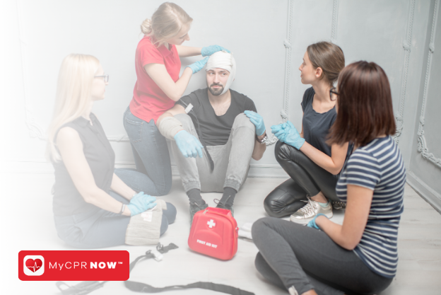 A group of people around somone getting a head bandage. 