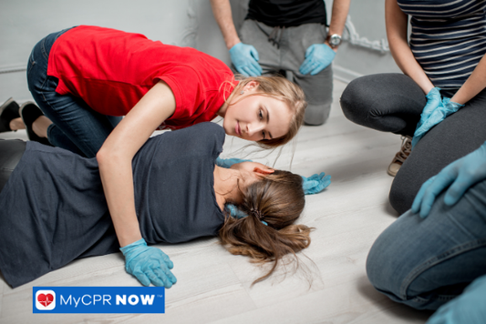 Woman checking the breathing of a person lying on the floor during a first aid scenario.