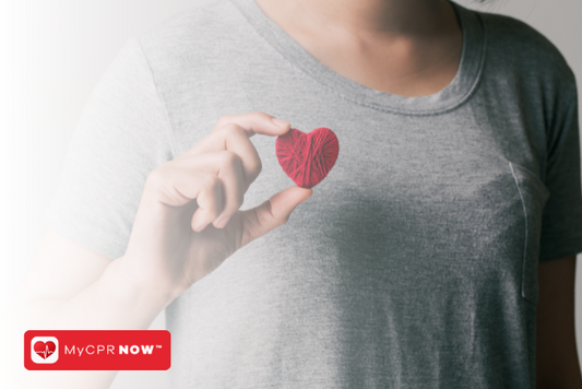 Someone holding a red heart made of string. 