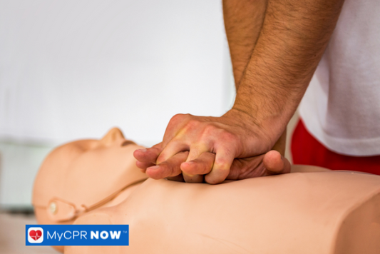 A close-up of hands performing chest compressions on a CPR manikin.
