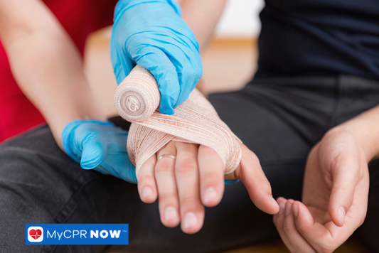 A gloved person wrapping a bandage around someone’s hand.