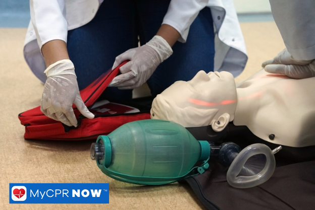 CPR mannequin with a bag valve mask being used in a medical setting.