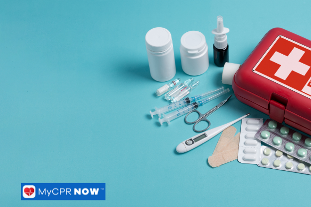 A red first aid kit with medical supplies, including syringes, pills, and bandages, arranged on a blue background.