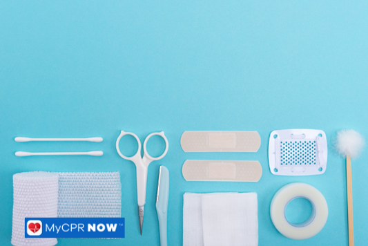 Various first aid items, including bandages, scissors, and cotton swabs, neatly arranged on a blue background.