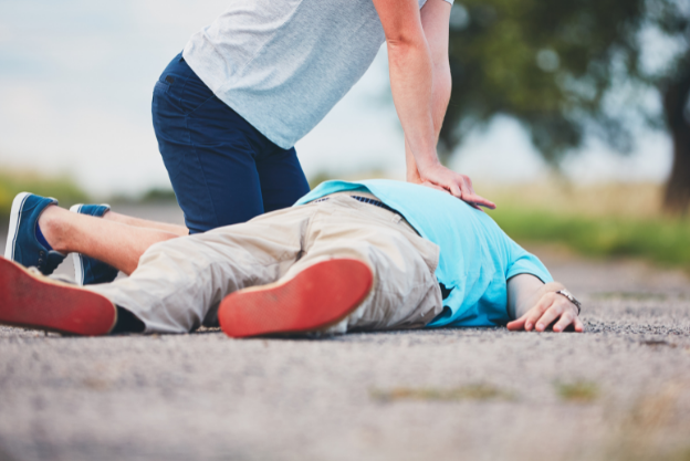 Someone performing CPR on a person laying on the road outside. 