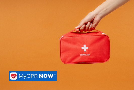 A hand holding a red first aid kit on an orange background.