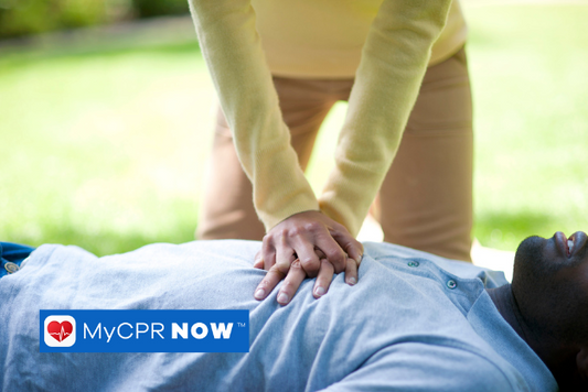 Someone in a yellow long sleave shirt performing CPR chest compressions on someone in a light blue shirt laying on the ground outside. 
