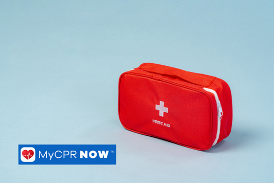 A red first aid kit with a white cross on the front against a blue backgound.