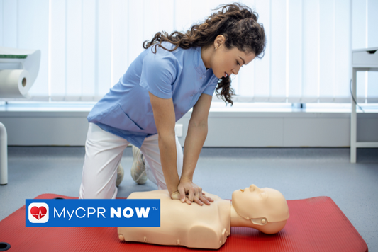 Someone practicing CPR compressions on a CPR mannequin in a room. 