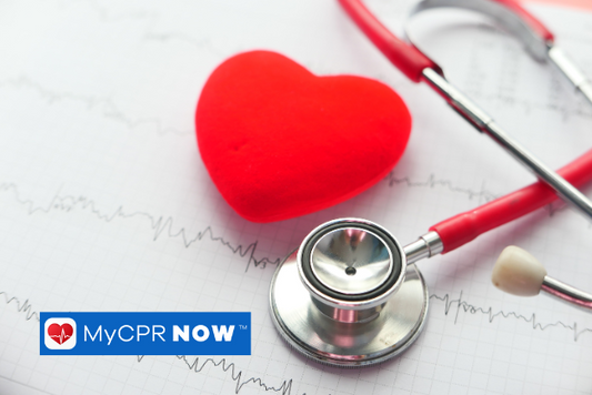 A red heart shape with a red stethoscope behind it on a sheet of heart lines. 