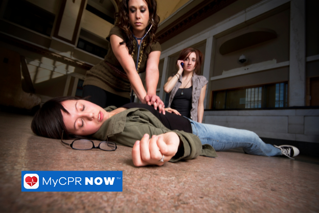 Woman lying the floor with black eye glasses next to her head. A woman on the phone and another woman doing CPR 