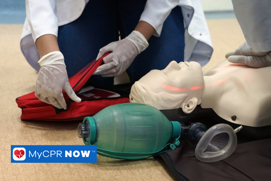 Basic Life Support training with a first aid kit, manikin dummy, and other equipment laid out on the floor