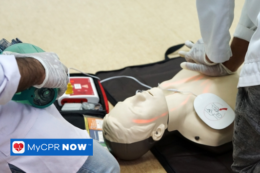 A man operating an automated external defibrillator on a dummy during a training session.