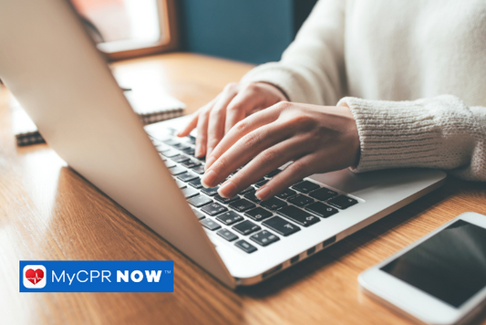 A woman seated at a desk and typing on a laptop