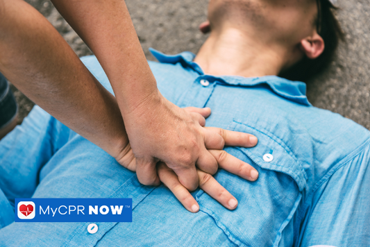 A man is on his back with a blue shirt and another person is performing CPR chest compressions to save a life